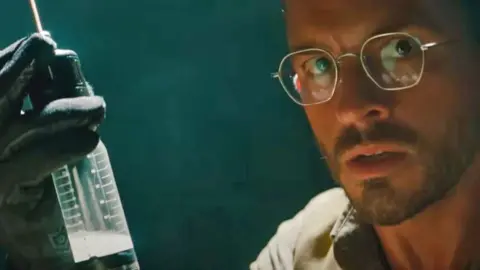 Universal Pictures Jonathan Bailey in character in a promotional still of the film Jurassic World: Rebirth (2025)