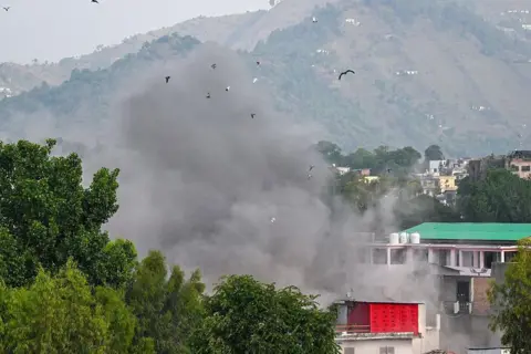 AFP via Getty Images Smoke billows after an artillery shell landed in the main town of Poonch district in India's Jammu region on May 7, 2025. At least eight Indians were killed and 29 others wounded Wednesday in the town of Poonch in Kashmir, close to the de facto border with Pakistan, a local Indian government official said. (Photo by Punit PARANJPE / AFP) (Photo by PUNIT PARANJPE/AFP via Getty Images)