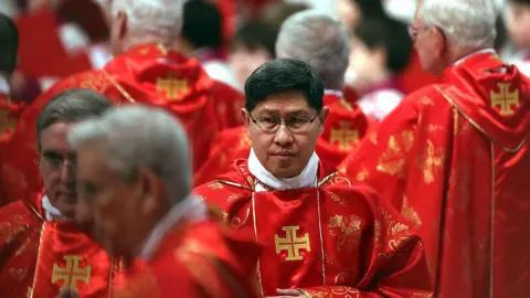 Getty Images Cardinal Luis Antonio Tagle pictured in red robes with other priests at the St Peter's Basilica