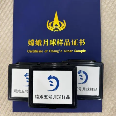 Mahesh Anand A blue folder that contains a certification from the Chinese space agency about the Chang'e 5 samples. On top are three boxes with white background and black borders. On the front is the Chinese space agency Chang'e logo and writing in Chinese script.