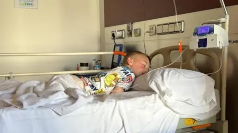 Contributor photo Michael, a young boy with fair hair, asleep in his hospital bed