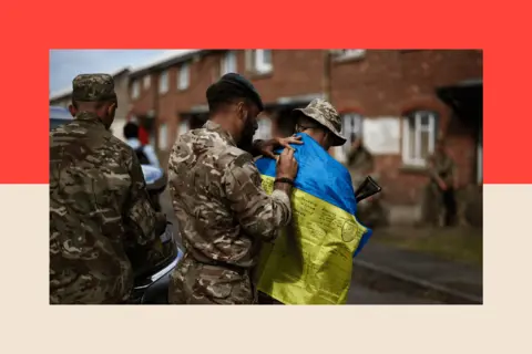 AFP/Getty Images A member of Britain's RAF Regiment signs the Ukraine's flag of a Ukraine Army