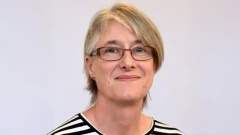 University of Bristol School for Policy Studies A portrait photo of Prof Hester, who smiles into the camera. She is wearing glasses, a striped top and her hair is cut short.