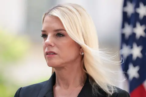 Getty Images Pam Bondi looking off camera with an American flag in the background