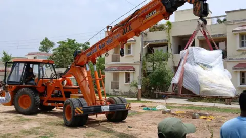 A photo of a crane lifting up the skeleton from the site in western Gujarat state, India. 