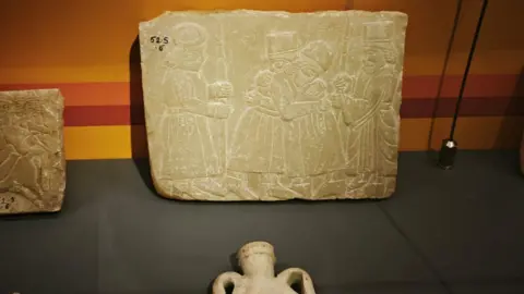 A photo of a cuneiform tablet that depicts people dressed in Persian attire greeting each other displayed at Mumbai's newly renovated Parsi museum. 