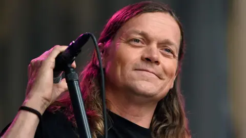 Getty Images Brad Arnold standing on stage next to a microphone stand