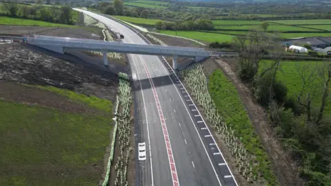 BBC An aerial view of the improved A40 showing an overhead bridge and the surrounding countryside.