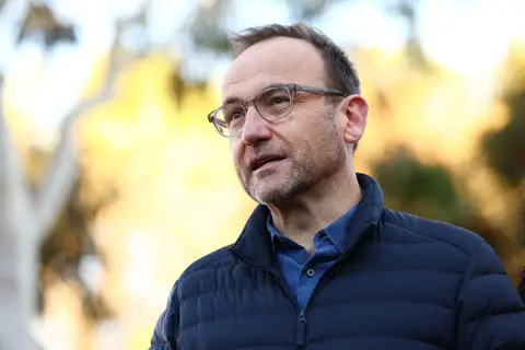 Getty Images Adam Bandt in glasses and a puffer jacket