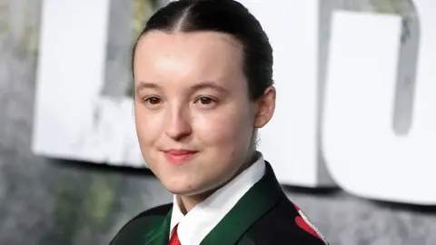 Getty Images Bella Ramsey at the Last of Us premiere wearing a dark green suit and red tie
