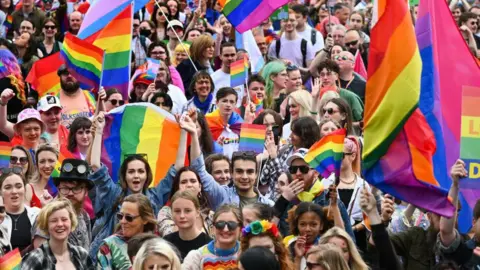 Getty Images Crowds waving rainbow banners on a march