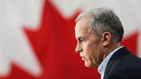 Getty Images Mark Carney seen from the side, with the Canadian flag in the background