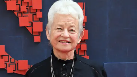 Getty Images Dame Jaqueline Wilson wearing a black top and two silver necklaces. She has white cropped hair.