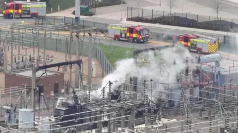 PA Media Smoke comes from a power station while three fire engines are seen in the background