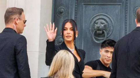 EPA Kim Kardashian waves to gathered press and public upon arriving at the court in Paris on Tuesday to give evidence