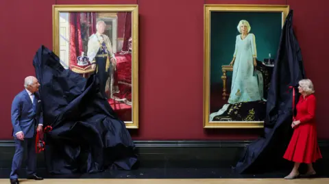PA Media King Charles and Queen Camilla removing covers from portraits depicting them