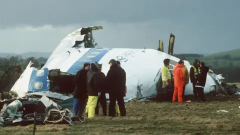 Reuters Emergency service personnel standing next to the fuselage of Pan Am flight 103 after it was downed over Lockerbie.