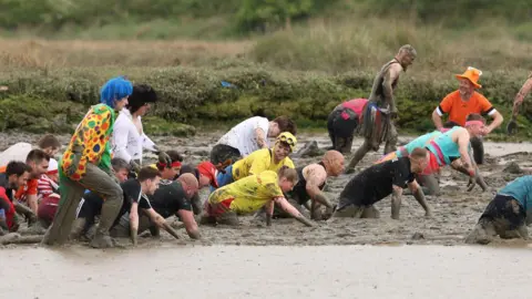 Chris Radburn/BBC People in fancy dress and none taking part in the Maldon Mud Race, across the River Chelmer, fighting and crawling their way to the finish line
