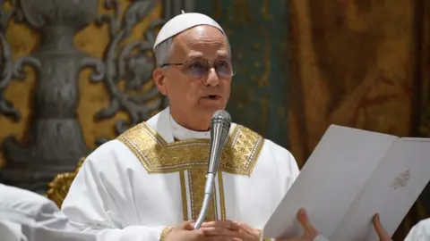 Reuters Pope Leo XIV speaking into a microphone in his first mass at the Vatican