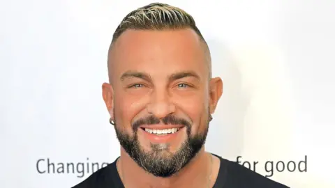 Robin Windsor/Sane Robin Windsor in a black T-shirt. He is looking directly at the camera