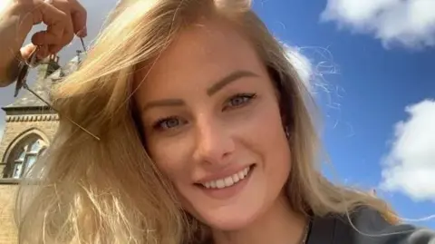 BBC Jade Damarell is smiling at the camera. She has long blonde hair and is holding a pair of sungalsses.