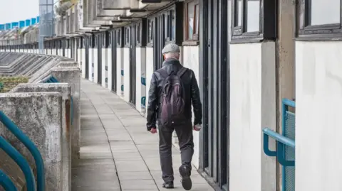 Getty Images An unidentified man walking on the crescent walkway of Alexandra Road estate in London, UK
