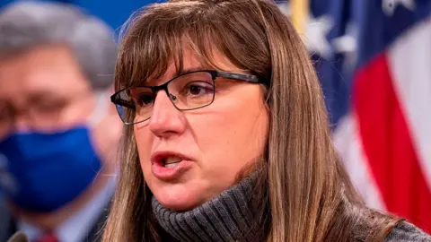 Getty Images Kara Weipz in a polo neck, wearing glasses; she has long brown hair