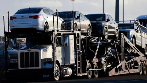 Getty Images Vehicles are parked on car carrier trailers ready for distribution at a vehicle processing lot at the National City Marine Terminal, a major port for vehicle imports and exports, particularly for new foreign cars entering the United States on April 26, 2025 in National City, California