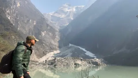 BBC BBC World Service environment correspondent Navin Singh Khadka trekking with mountains visible behind him