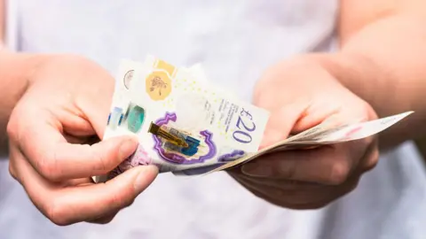 Getty Images Counting out UK cash - stock photo
Close-up as a woman counts out modern British banknotes. All you can see are her hands.