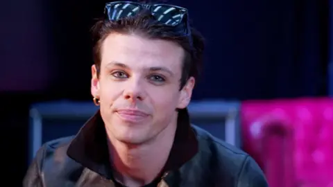 BBC A head and shoulders image of Yungblud, who is wearing a leather jacket and sunglasses on his head while looking into the camera