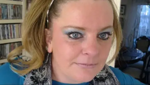 Supplied Jodey Whiting is looking towards the camera. She has blonde shoulder-length hair with a silver hairband and is wearing a a silver coloured scarf and a light blue jumper
