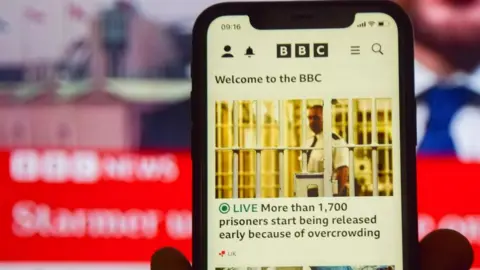 Getty Images In this photo illustration, a BBC News website seen displayed on phone and TV screens