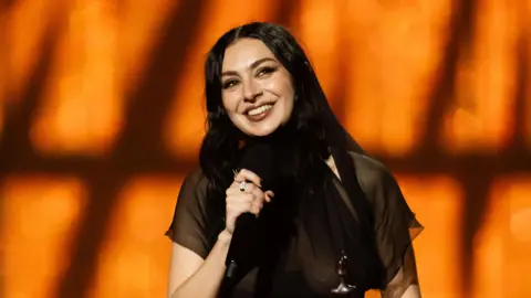 Getty Images Charli XCX smiles holding microphone