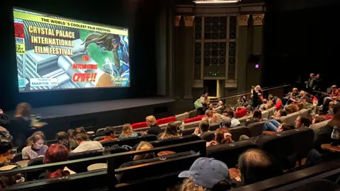 Lee Bolton Photography Crystal Palace's Everyman cinema shows rows of cinemagoers looking at a CPIFF poster with the words 'the astonishing CPIFF'