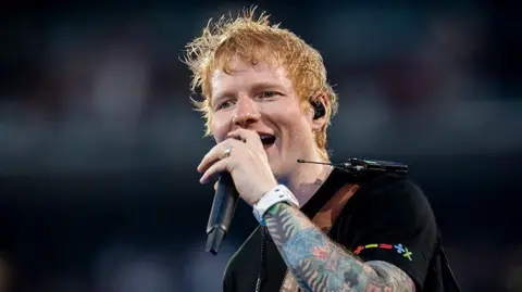 Getty Images Ed Sheeran singing at a concert in Madrid. He is wearing a black T-shirt.