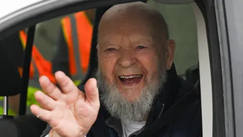 Reuters Michael Eavis smiles and waves at the camera from the window of his van