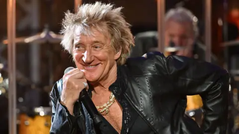 Mark Allan / BBC Rod Stewart, dressed in black leather, smiles as he leans on a piano top, during a recording of the BBC's Later... With Jools Holland