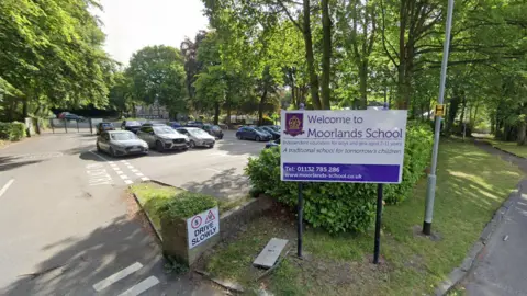 Google A white and purple sign outside a car park that reads: Welcome to Moorlands School