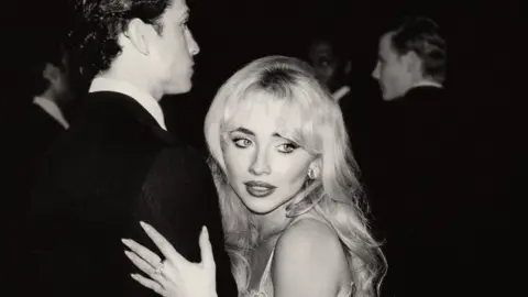 Island Records Black and white image of Sabrina Carpenter holding a man's arm