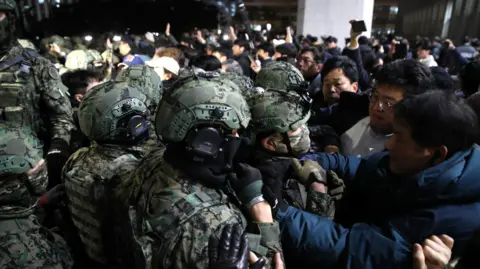 Getty Images Soldiers in South Korea try to detain protesters during the imposition of martial law