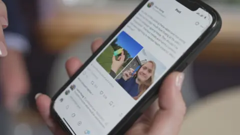 BBC A smart phone held in the hand shows the first tweet by Laura Young about vapes, with pictures of her holding the devices she found