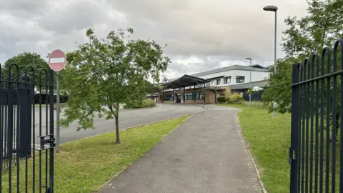 Forest Oak and Merstone schools. We see the path leading up to the schools from behind a gate.
