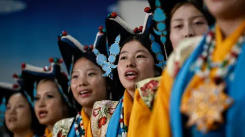 Reuters Tibetan girls in traditional attire perform during an event organised to mark the 90th birthday celebration of their spiritual leader