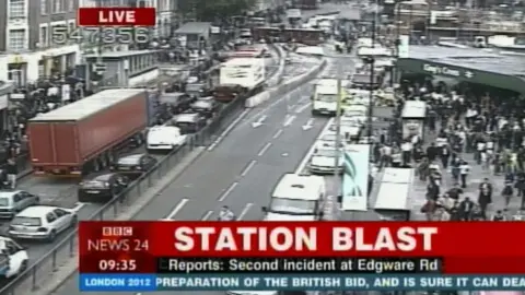 A photo of BBC News 24 TV channel at 0935 on the day of the blast.  The caption says "station blast" and underneath "Reports: second incident at Edgware Rd". A large crowd can be seen outside Kings Cross overground station with traffic backed up on the opposite side of the road.