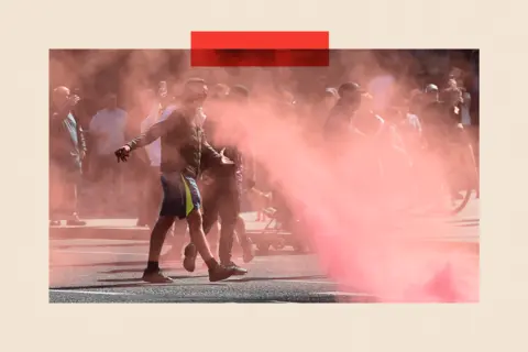 Peter Powell/AFP via Getty Images Protesters throw flares in Liverpool during a demonstration held in reaction to the fatal stabbings in Southport on July 29
