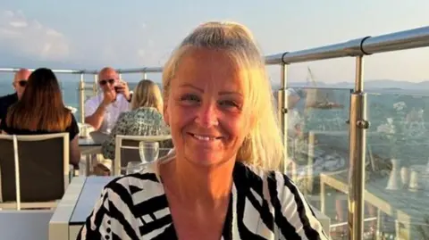 Suffolk Police A photo of Anita Rose smiling directly into the camera. She appears to be sitting at a table in a restaurant on a high-rise terrace. Other diners can be seen in the background.