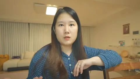 Jang Sae-ryeon A woman, wearing a blue shirt, stares at the camera. 