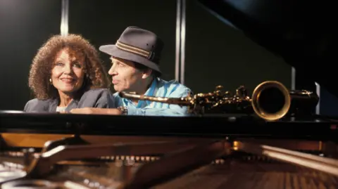 Getty Images Dame Cleo Laine and her husband Sir John Dankworth at the piano