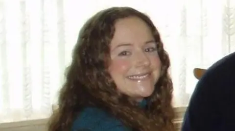 Family handout A young women with brown wavy hair is looking at the camera and smiling.  She is wearing a blue jumper